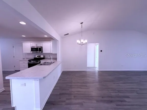 a large kitchen with kitchen island a sink dishwasher a refrigerator and a stove with wooden floor