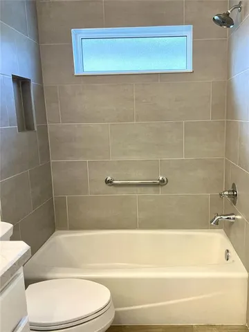a bathroom with a white bath tub a toilet and a sink