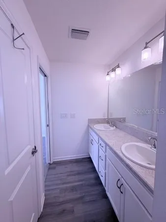 a spacious bathroom with a double vanity sink a large mirror and shower