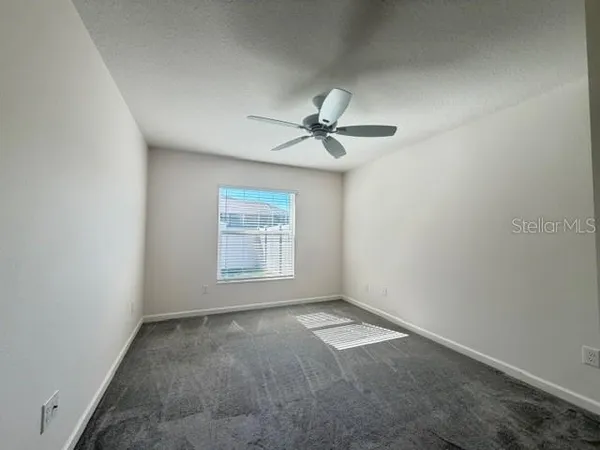 an empty room with a window and a fan