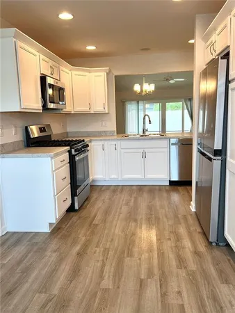 a large kitchen with stainless steel appliances granite countertop a stove a sink dishwasher and a refrigerator with wooden floor