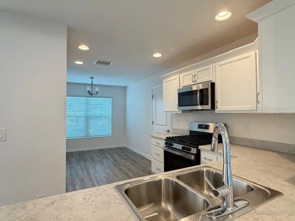 a kitchen with granite countertop a sink stainless steel appliances and cabinets