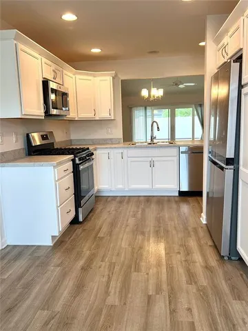 a large kitchen with stainless steel appliances granite countertop a stove a sink dishwasher and a refrigerator with wooden floor