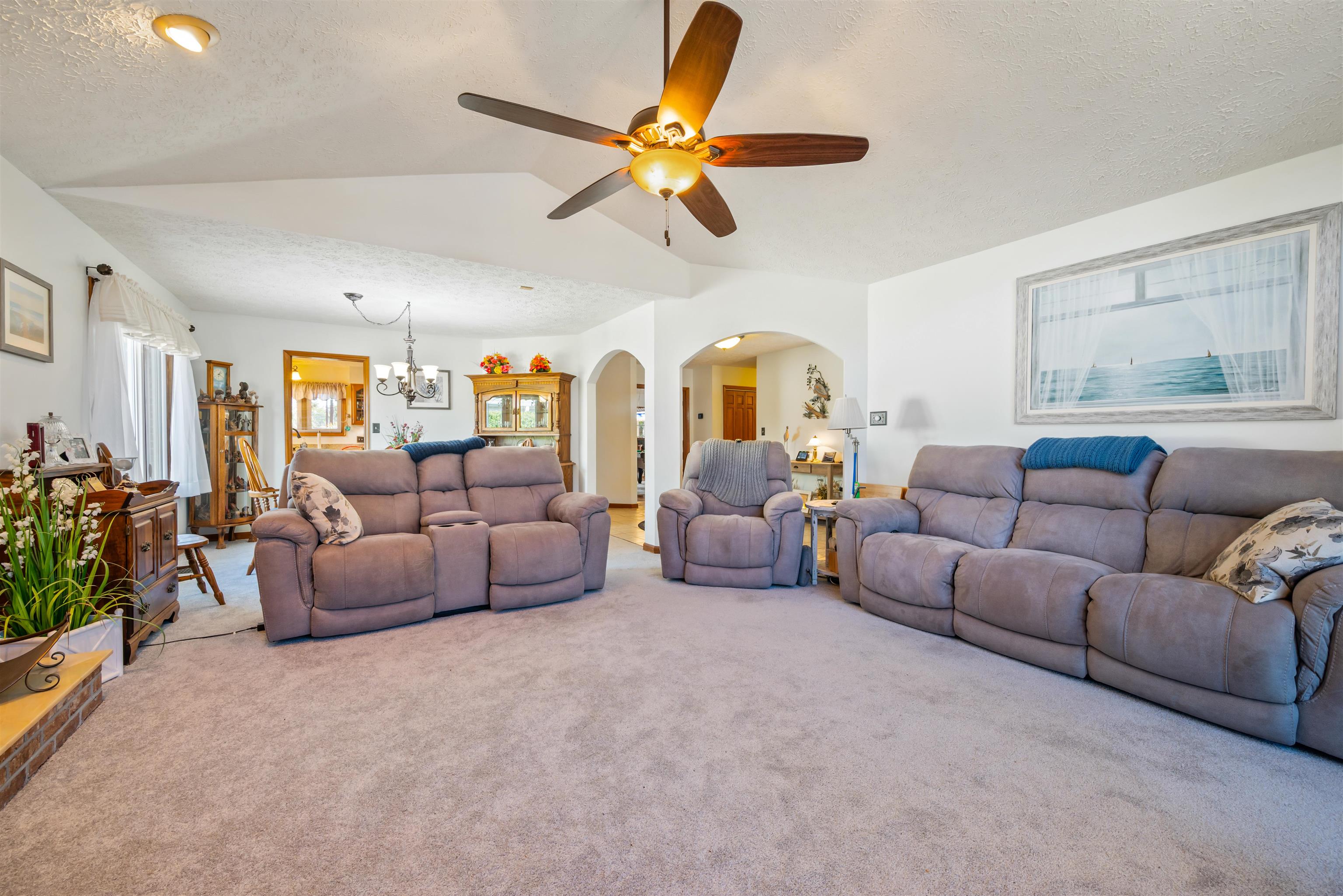 4746 National Drive Myrtle Beach, SC 29579 - Photo 10 of 40 Carpeted living area featuring a chandelier, a textured ceiling, vaulted ceiling, arched walkways, and ceiling fan