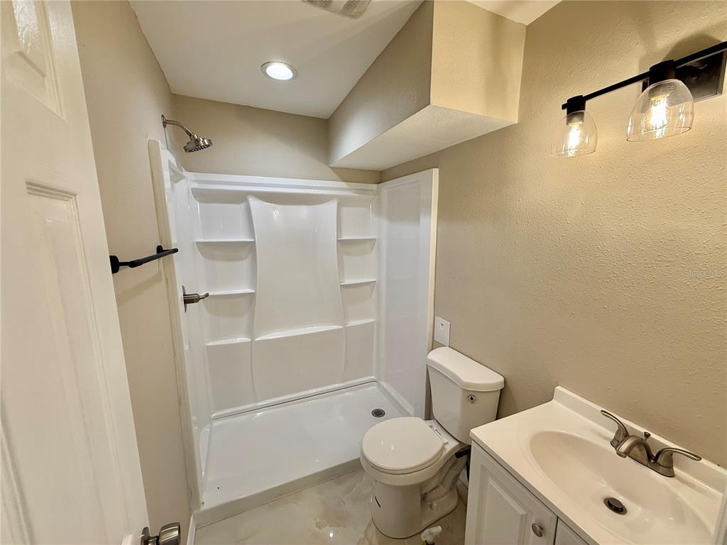 2769 L B McLeod Road, Unit 2769A Orlando, FL 32805 - Photo 12 of 15 a white toilet sitting next to a bathroom sink and a shower