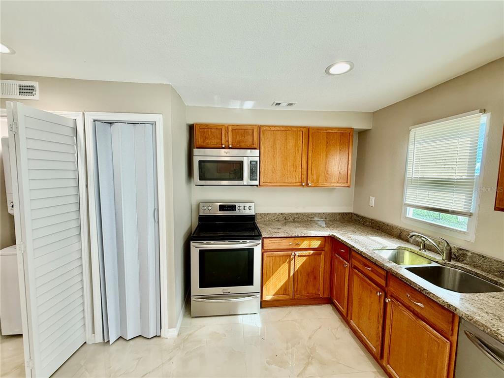 2769 L B McLeod Road, Unit 2769A Orlando, FL 32805 - Photo 5 of 15 a kitchen with stainless steel appliances granite countertop a sink stove and refrigerator