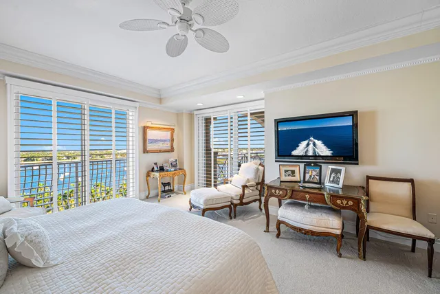 a spacious bedroom with a bed and a flat tv screen on dresser