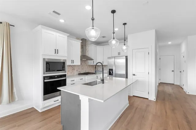 a large kitchen with stainless steel appliances a large center island attached withe living room