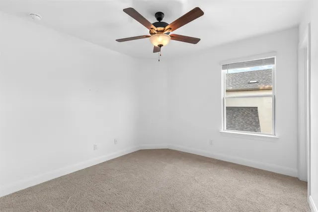 an empty room with a window and a ceiling fan