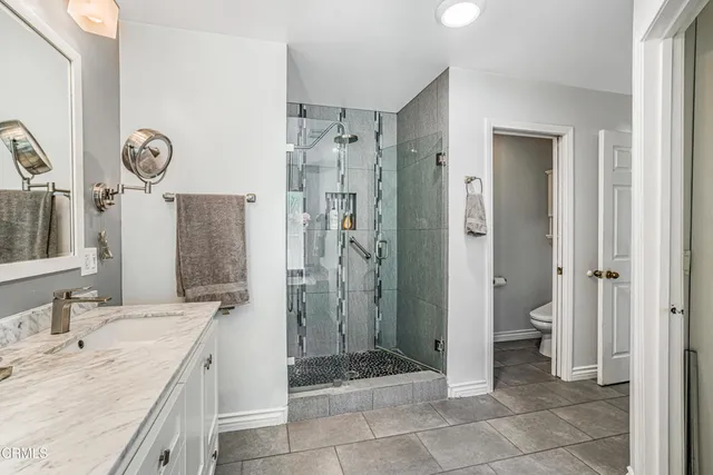 a bathroom with a granite countertop sink a toilet and a shower