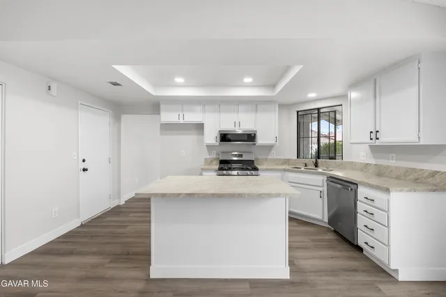 a kitchen with stainless steel appliances granite countertop a stove a sink a refrigerator and white cabinets