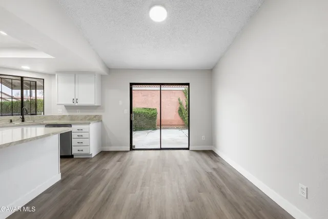 an empty room with windows and chandelier fan