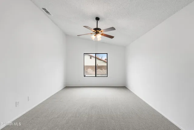 a view of empty room with a ceiling fan and window