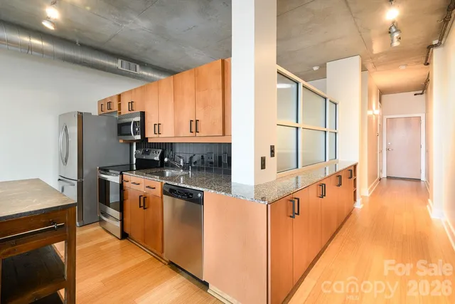 a kitchen with stainless steel appliances granite countertop a stove a sink and a microwave