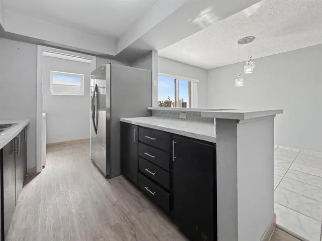 a kitchen with a sink a refrigerator and wooden floor