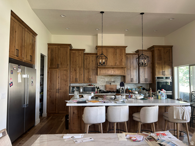 2688 Read Lane Preston, ID 83263 - Photo 6 of 18 Spacious kitchen featuring extensive wood cabinetry, a large center island with seating, stainless steel appliances, dual wall ovens, and custom pendant lighting fixtures
