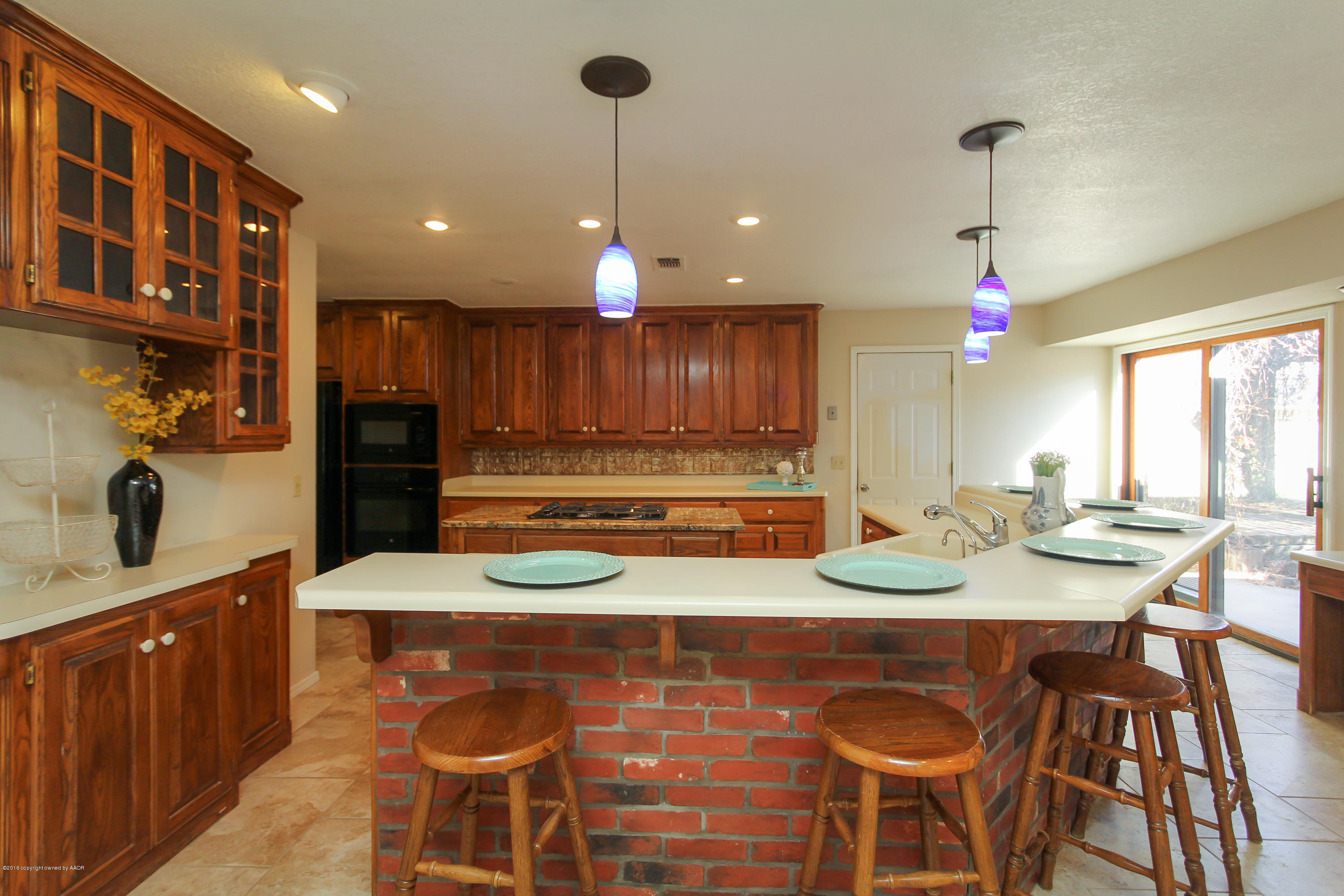 7915 Santa Fe Trail Amarillo, TX 79110 - Photo 16 of 57 a kitchen with kitchen island granite countertop wooden cabinets and a refrigerator