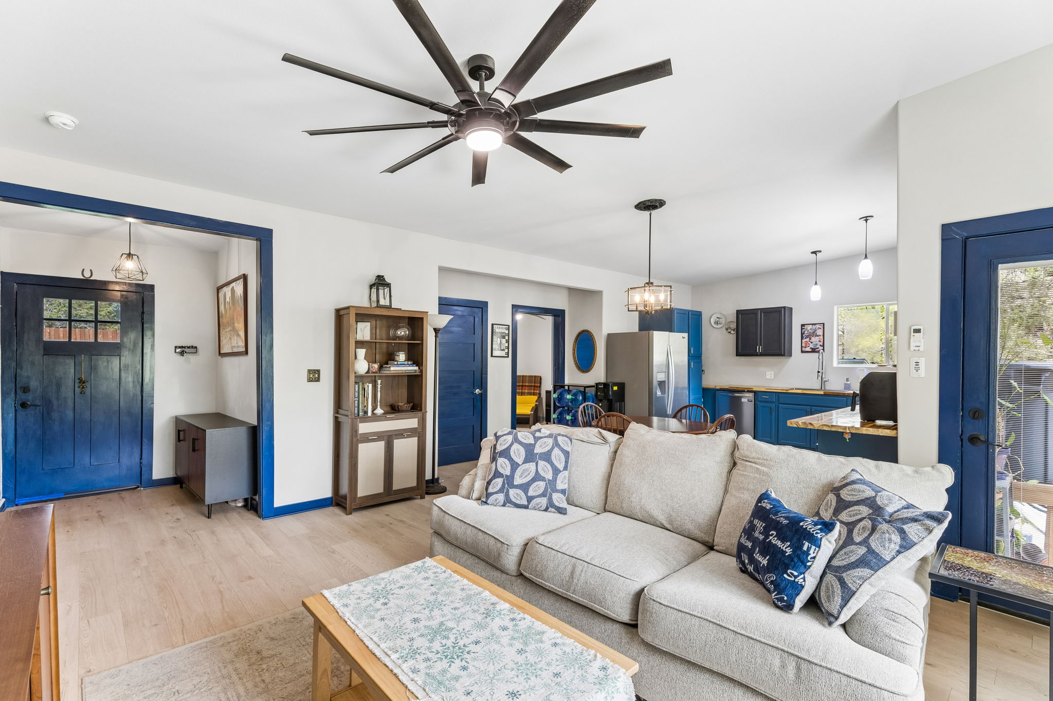 The living area features light-colored flooring, a ceiling fan with integrated lighting, and white walls with contrasting blue trim