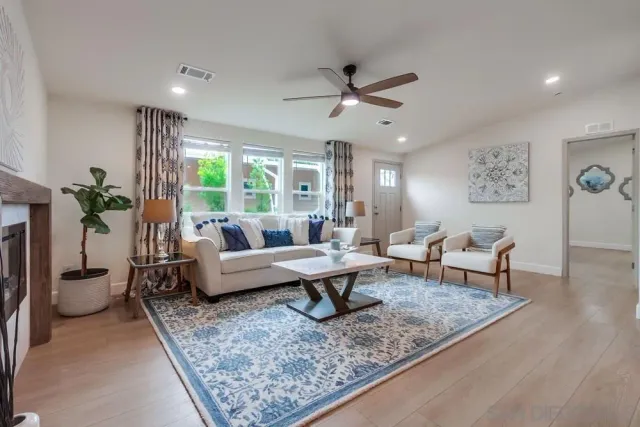a living room with furniture kitchen view and a wooden floor