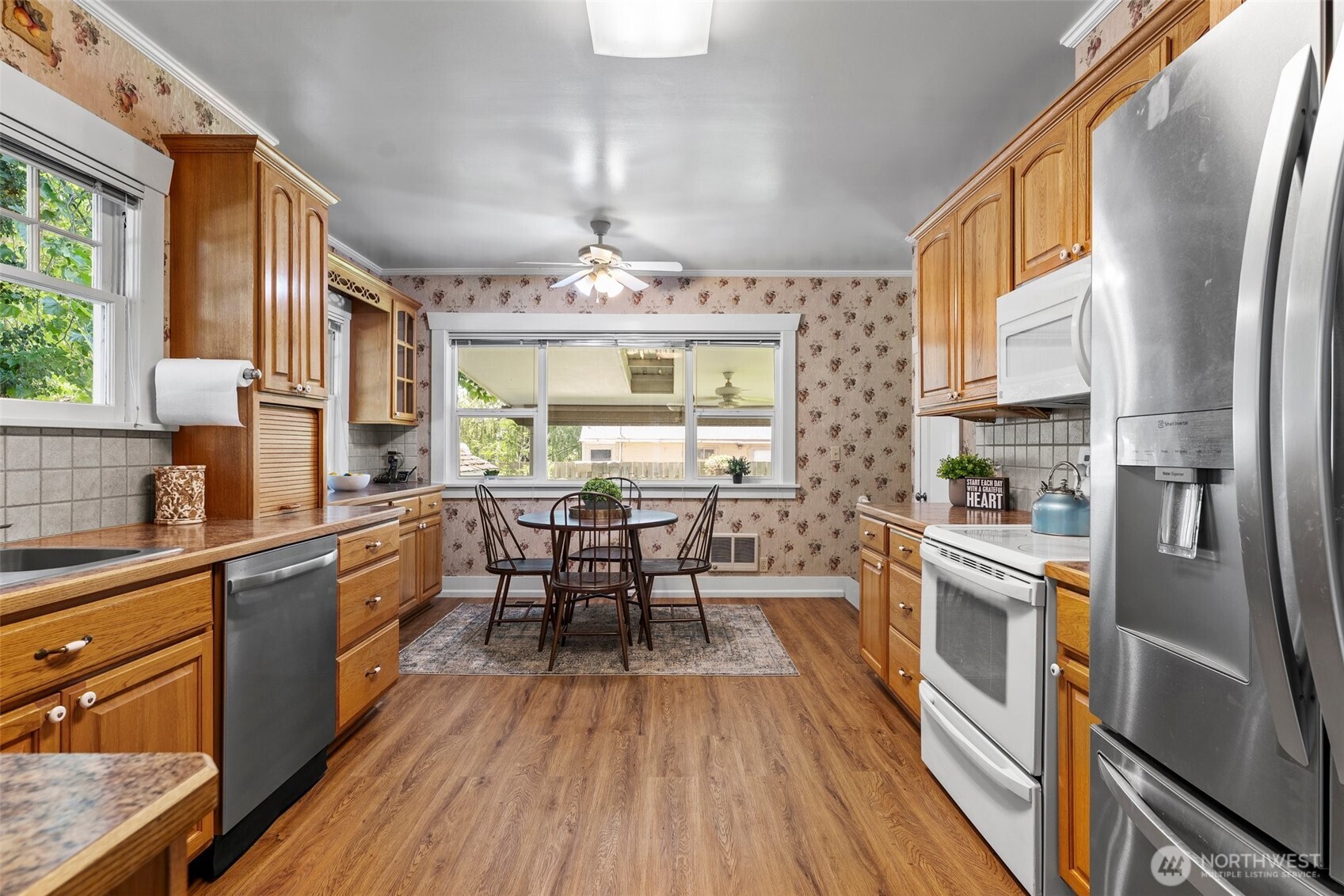 1121 Scoon Road Sunnyside, WA 98944 - Photo 17 of 39 a kitchen with stainless steel appliances a table chairs refrigerator and wooden floor