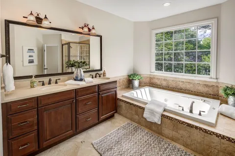 a bathroom with a tub double vanity sink a window and a mirror