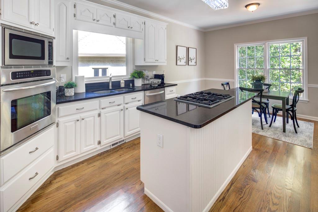 2059 Howell Mill Road Northwest Atlanta, GA 30318 - Photo 7 of 28 a kitchen with granite countertop a stove top oven a sink dishwasher a dining table and chairs with wooden floor