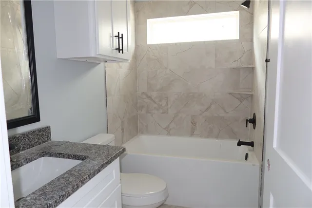 a bathroom with a granite countertop bathtub shower sink vanity and mirror