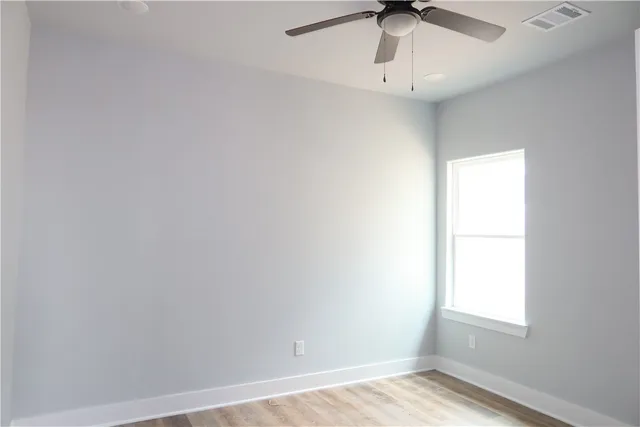 an empty room with a window and a ceiling fan