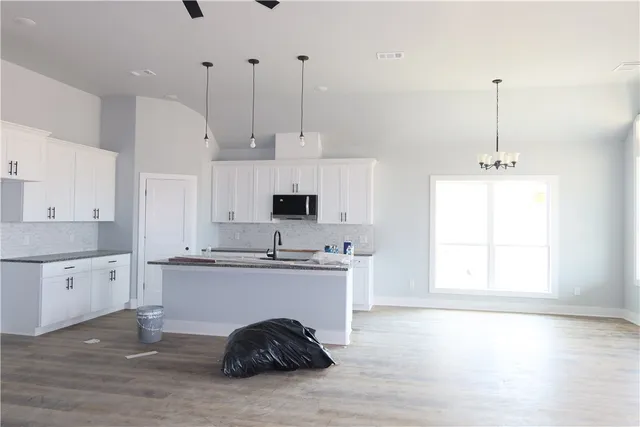 a kitchen with kitchen island granite countertop a stove a sink a center island and a window