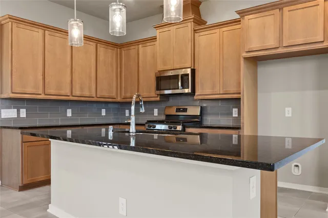 a kitchen with stainless steel appliances granite countertop a sink a stove and microwave