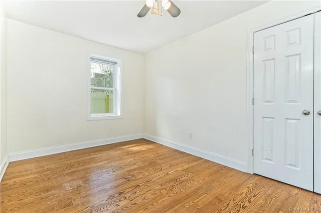 an empty room with a window and a chandelier fan
