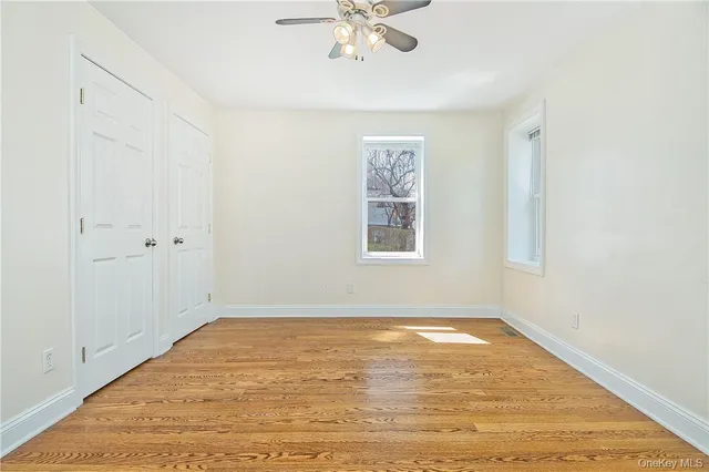 an empty room with a window and a ceiling fan