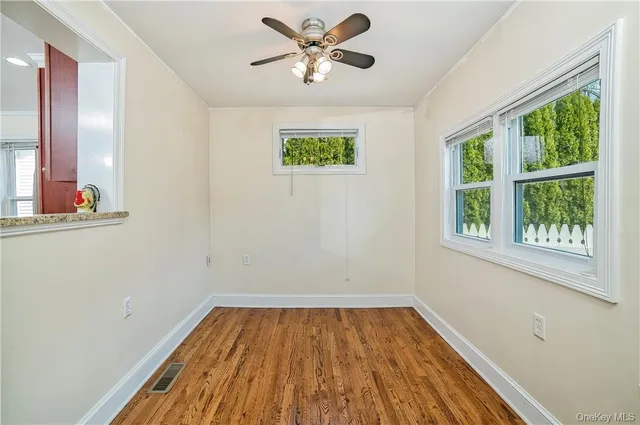 a view of an empty room with window and wooden floor