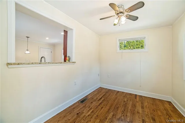 a view of a room with wooden floor and a ceiling fan