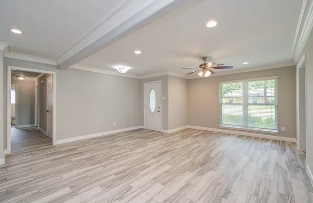 a view of an empty room with wooden floor and a window
