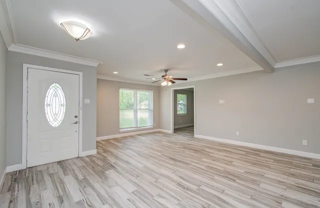 a view of an empty room with window and wooden floor