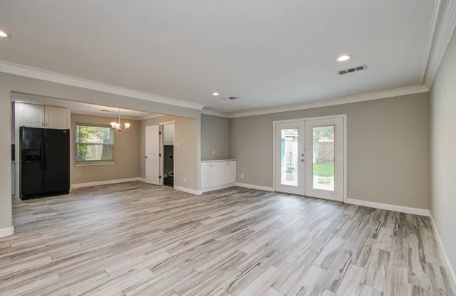a view of an empty room with window and wooden floor