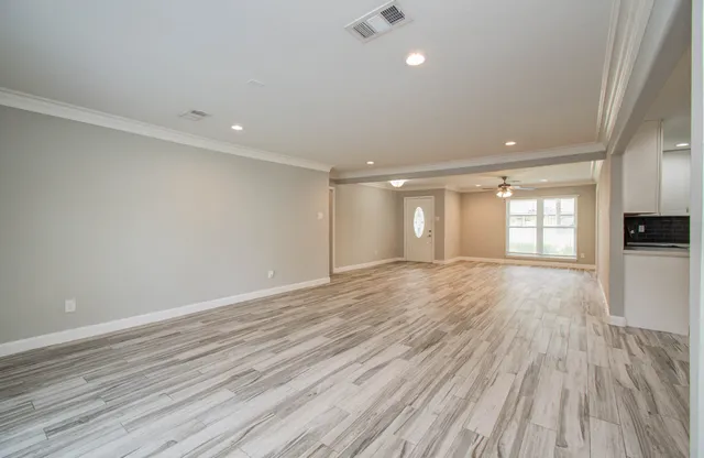 a view of an empty room with wooden floor and a window
