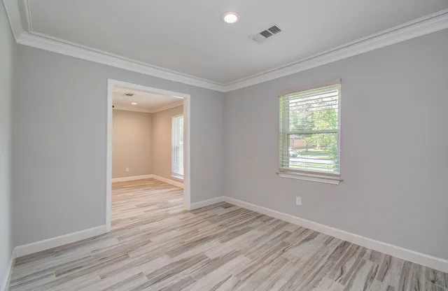 an empty room with wooden floor and windows