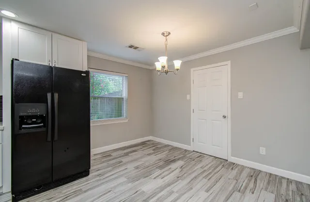 an empty room with wooden floor closet and chandelier