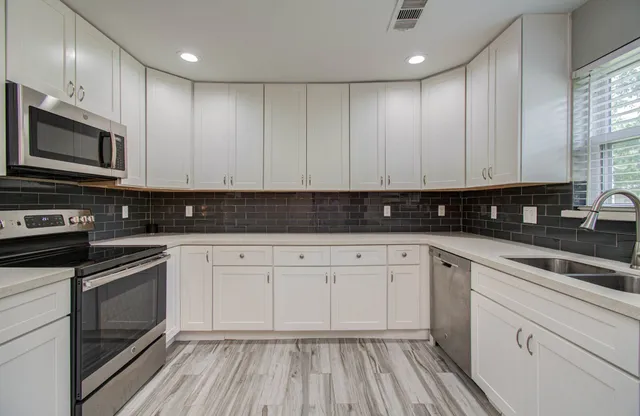 a kitchen with stainless steel appliances granite countertop a stove a sink and white cabinets