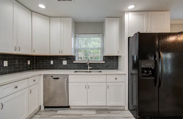 a kitchen with white cabinets and refrigerator