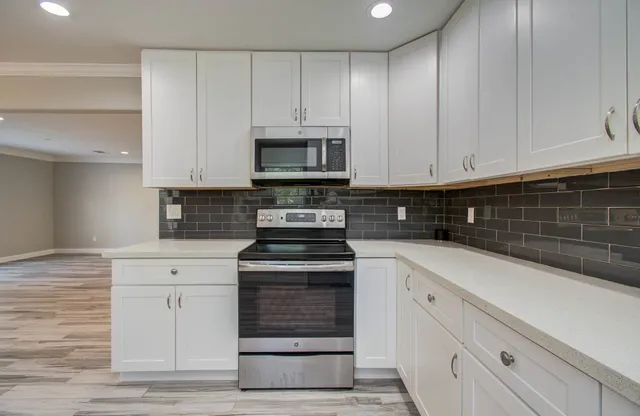 a kitchen with granite countertop white cabinets and stainless steel appliances