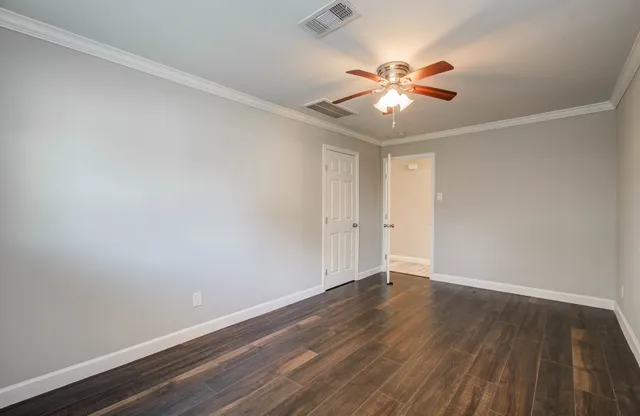 an empty room with wooden floor fan and windows