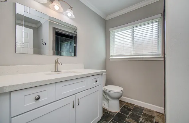 a bathroom with a sink a toilet and a window