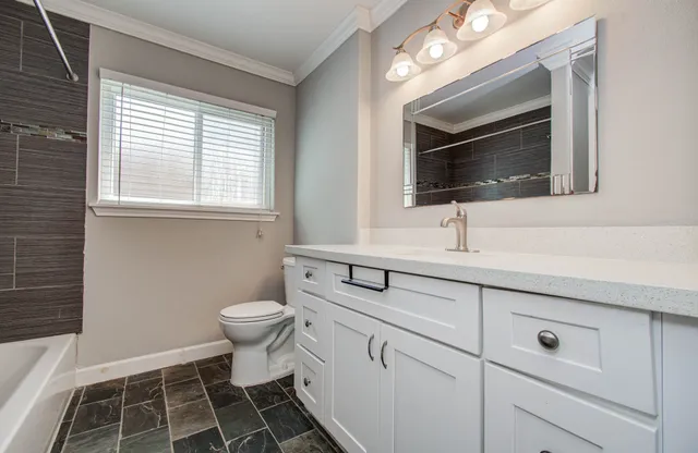 a bathroom with a sink toilet a mirror and window