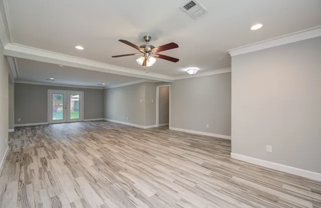 a view of empty room with wooden floor and fan