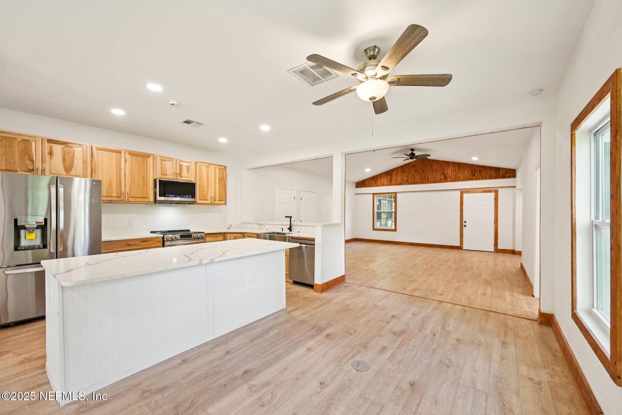 1217 Colley Road Starke, FL 32091 - Photo 13 of 42 a kitchen with stainless steel appliances a stove top oven a refrigerator a sink with white cabinets and wooden floor