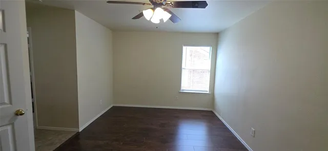 an empty room with wooden floor chandelier fan and windows