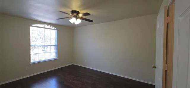 a view of a room with wooden floor and a ceiling fan